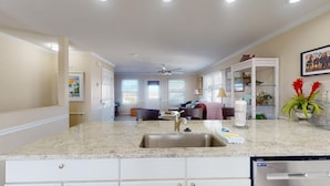 A kitchen with a granite countertop, a stainless steel sink, and white cabinetry.