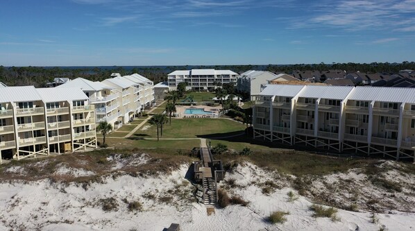 A coastal hotel with multiple-story buildings, a central pool, and a sandy beach area. - SeaCliffs North Cape San Blas (Cape San Blas)