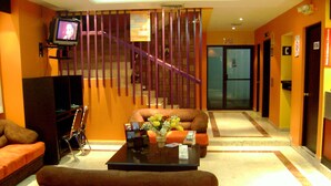 A lobby with a staircase, seating area, and a television mounted on the wall. - Hotel Le-Gar (Monterrey)
