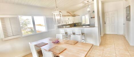 Een lichte keuken met witte kastjes, een houten keukeneiland en een hanglamp.