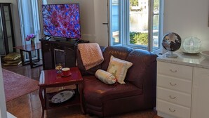 Een woonkamer met een leren bank, een televisie, een wereldbol en uitzicht op de natuur.