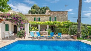 A stone house with a swimming pool, green shutters, and outdoor seating. - Finca LHort de Can Bota (Pollensa)