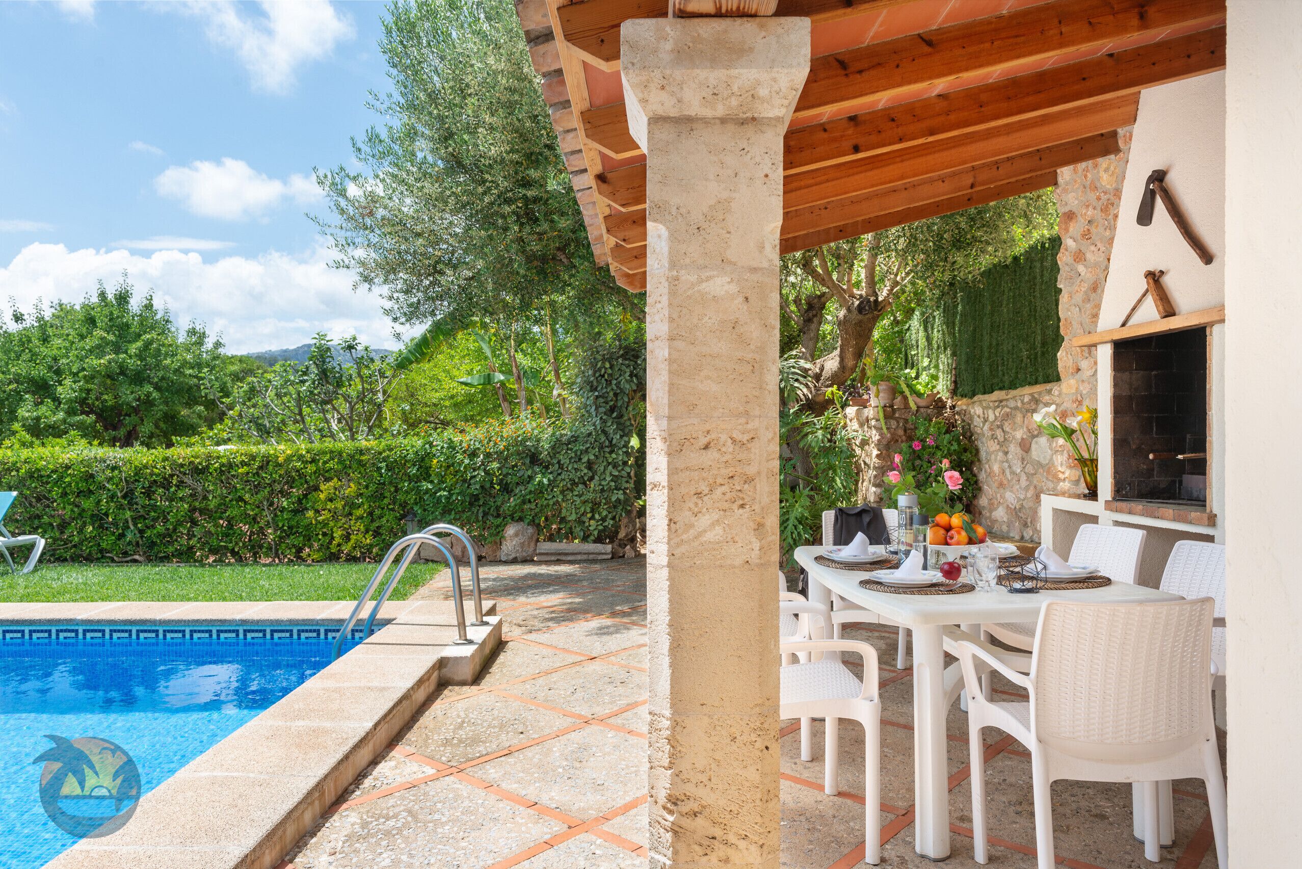 Ein Poolbereich mit einer Terrasse aus Steinplatten, einer Pergola und einem für das Essen gedeckten Tisch.