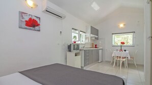Ein kompaktes Hotelzimmer mit Bett, Küchenzeile, Essbereich und Fenster mit Blick.