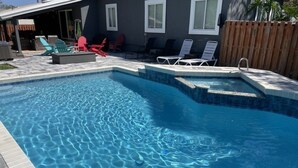 A swimming pool with clear water, surrounded by lounge chairs and a wooden fence. - Floridays Vacation Home with Pool near to beach by RedAwning (St. Augustine)
