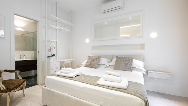 Un dormitorio moderno con una cama grande, un armario empotrado, una tocador con espejo y un aire acondicionado.