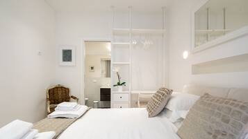 Un dormitorio moderno con una cama grande, una silla, un tocador y un vestidor.