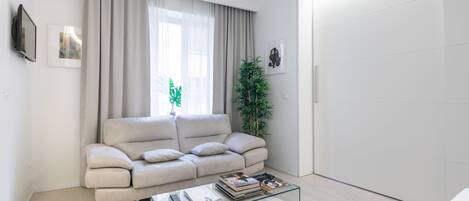 A modern living room with a beige sofa, a glass coffee table, and a plant.