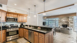 Una cocina moderna con electrodomésticos de acero inoxidable, armarios de madera y una pared de acento de piedra.