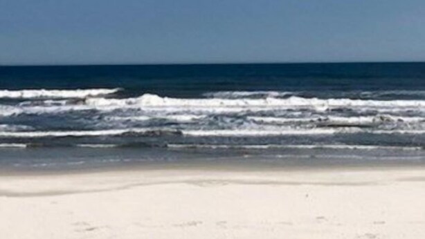 Ein Strand mit blauem Himmel und Meereswellen.