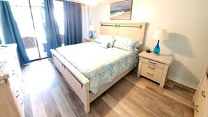 Ein Schlafzimmer mit einem Bett, Nachttischen, einem Fenster mit Vorhängen und einem Bild an der Wand.