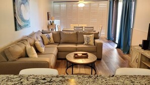 Ein Wohnzimmer mit einer Eckcouch, einem Couchtisch und einem Essbereich mit Tisch und Stühlen.
