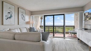 A living room with a sofa, a coffee table, and a TV. There are two framed artworks on the wall. - Island House A209 2 Bedroom Condo by RedAwning (St. Augustine)