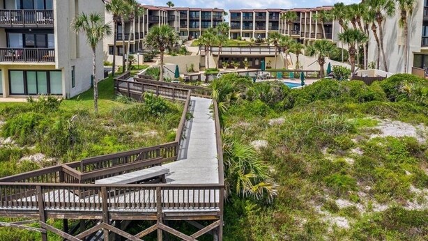 A resort with multiple-story buildings, a wooden boardwalk, and a pool area surrounded by greenery. - Island House A209 2 Bedroom Condo by RedAwning (St. Augustine)