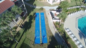 Ett poolområde på taket med en blå shuffleboard-bana, solstolar och en swimmingpool.