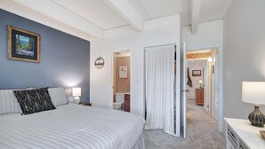 A bedroom with a large bed, a nightstand, a lamp, and a painting on the wall. - Ten Mile Creek 304 2 Bedroom Condo by RedAwning (Frisco)