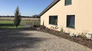 A house with a gravel driveway, a small tree, and a field in the background. - Vacation apartments Königsgut Emmericher Eyland (apartment 2) (Kalkar)