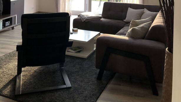 A modern living room with a sofa, coffee table, and a TV. There are skylights and a large window with curtains. - Vacation apartments Königsgut Emmericher Eyland (apartment 2) (Kalkar)