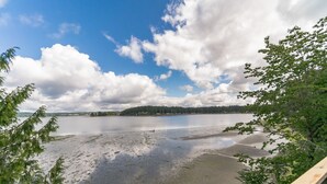 Blick auf einen See mit einer Holzterrasse, ruhigem Wasser und einem bewaldeten Ufer.