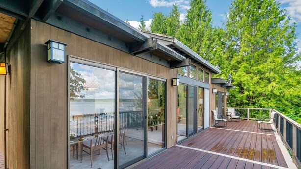 Ein modernes Haus mit Terrasse, großen Schiebegläsern und einer Satellitenschüssel.