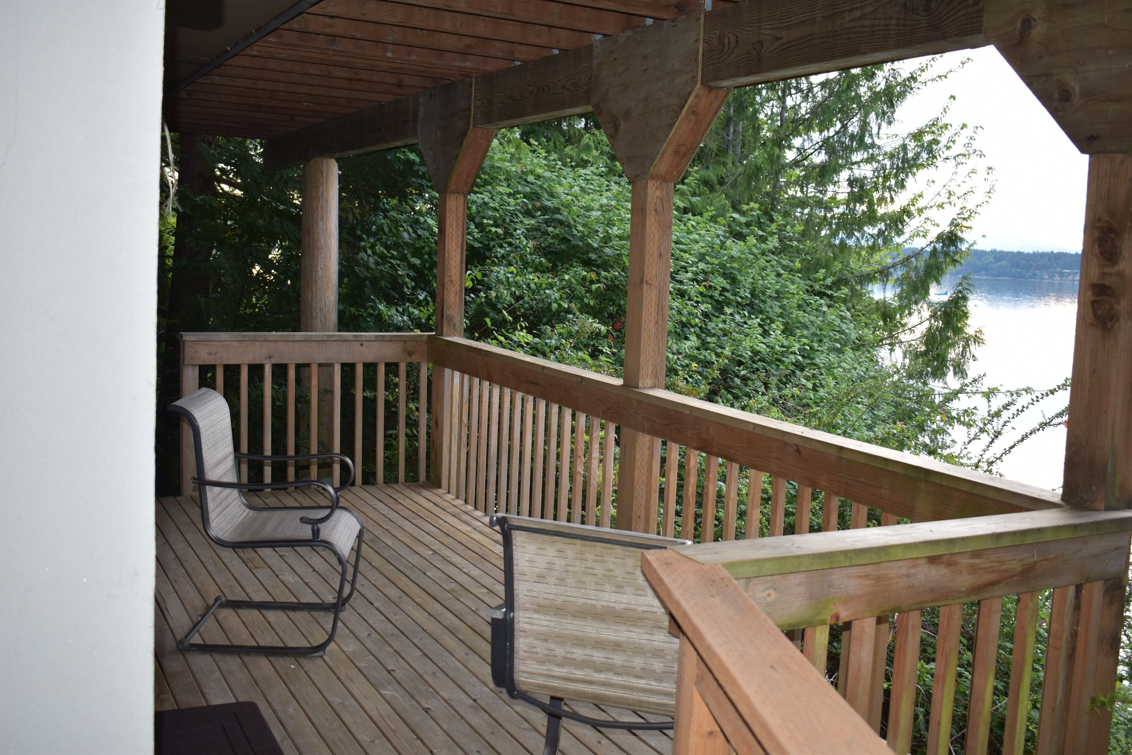 A wooden deck with two chairs and a view of a lake.