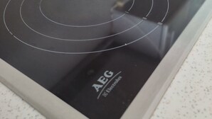 A kitchen with an induction cooktop labeled AEG.
