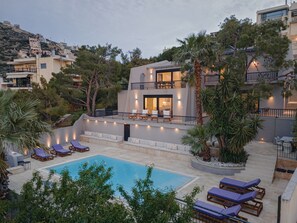 Un edificio moderno de dos pisos con piscina, mobiliario exterior y balcón.