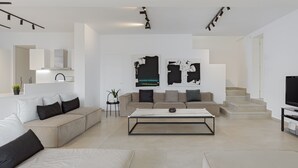 A modern living room with a sofa, coffee table, and abstract wall art. - Athenian Black Villa (Saronikos)