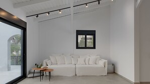 A modern living room with a white sofa, a small wooden table, and a patterned rug. - Athenian Black Villa (Saronikos)