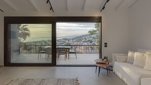A modern living room with a large sliding glass door leading to an outdoor balcony. - Athenian Black Villa (Saronikos)