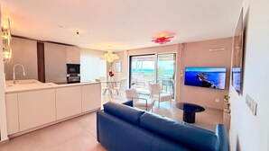 Een moderne woonkamer met een bank, een televisie en een eethoek met een tafel en stoelen.