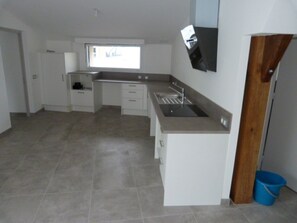 A kitchen with a built-in sink, white cabinets, and a window.