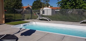 En rektangulär swimmingpool med en solstol och ett litet bubbelbad.