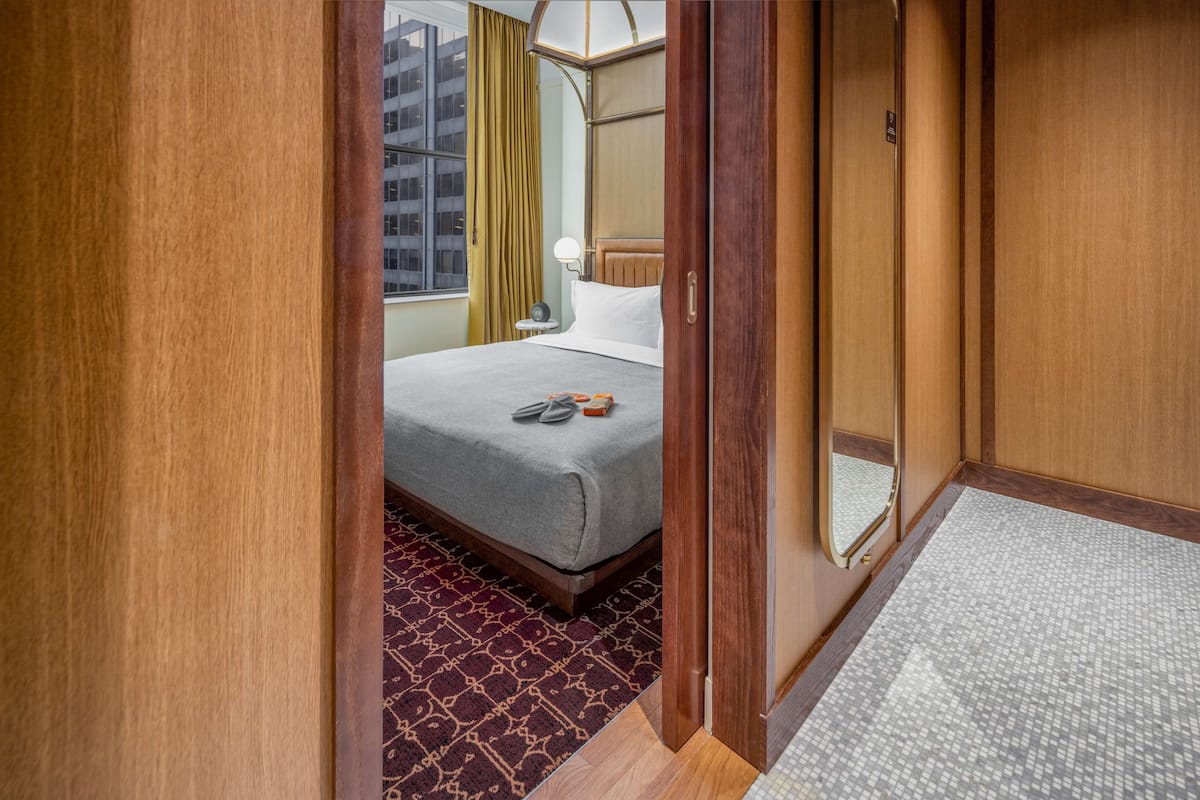 Una habitación de hotel con cama, una mesita de noche y una ventana con cortinas.