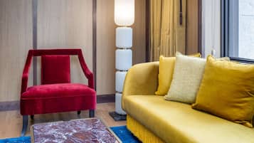 A room with a red chair, a yellow sofa, a floor lamp, and a marble table.