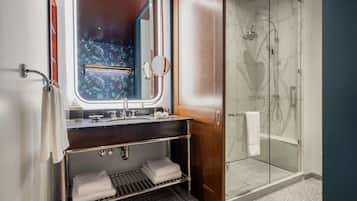 Une salle de bain avec un meuble-lavabo, un grand miroir, une douche avec des portes en verre et un porte-serviettes.