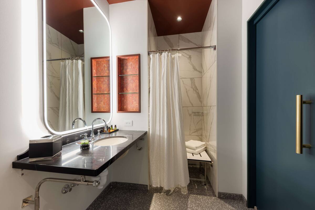 Un baño moderno con lavamanos doble, un espejo grande, ducha con cortina y una puerta azul.