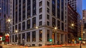 Un edificio grande e histórico con un estilo arquitectónico clásico, que cuenta con varios pisos y grandes ventanales.