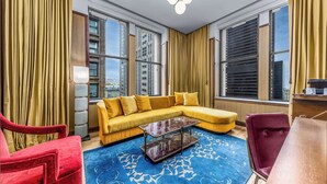 Una sala de estar moderna con un sofá seccional amarillo, un sillón rojo, un tapete azul estampado y una mesa de centro de mármol.