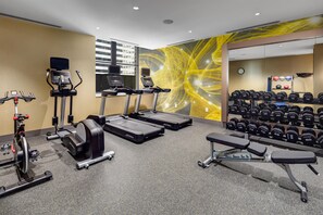 A gym with treadmills, a stationary bike, dumbbells, and a bench.