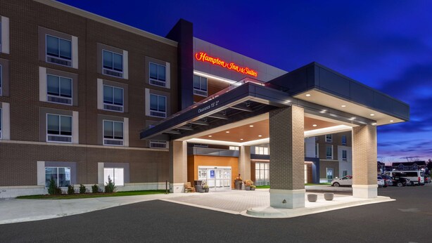 Un hôtel Hampton Inn & Suites doté d’une entrée bien visible, d’un espace de stationnement et d’une façade bien éclairée.