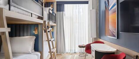 A room with bunk beds, a desk, two red chairs, a large window with sheer curtains, and a painting on the wall.