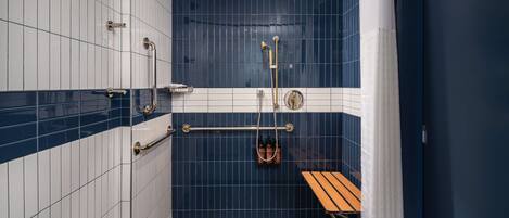 A small, enclosed shower area with a bench, a towel rack, and a hand dryer.
