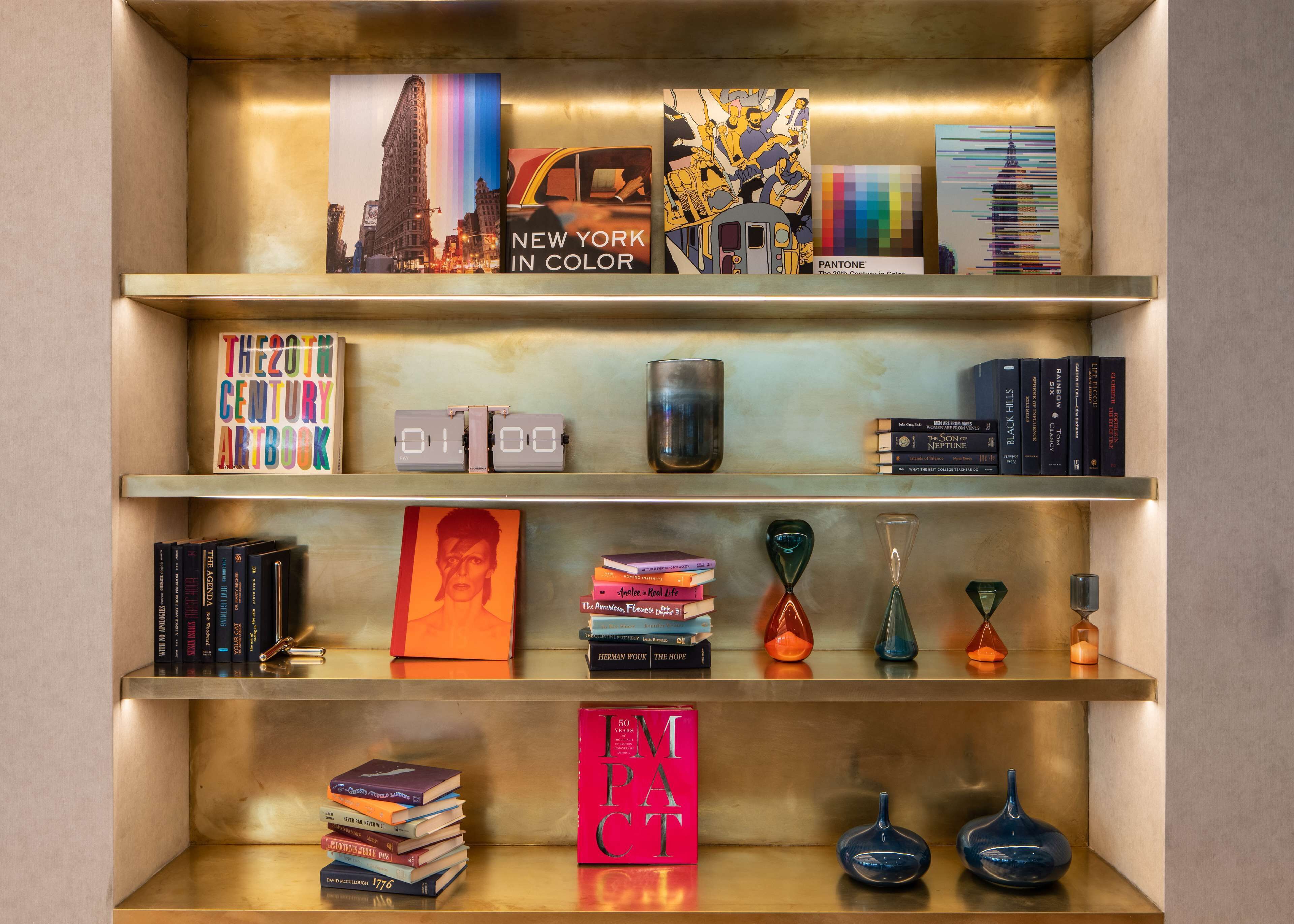 Una estantería con libros, un reloj y adornos.