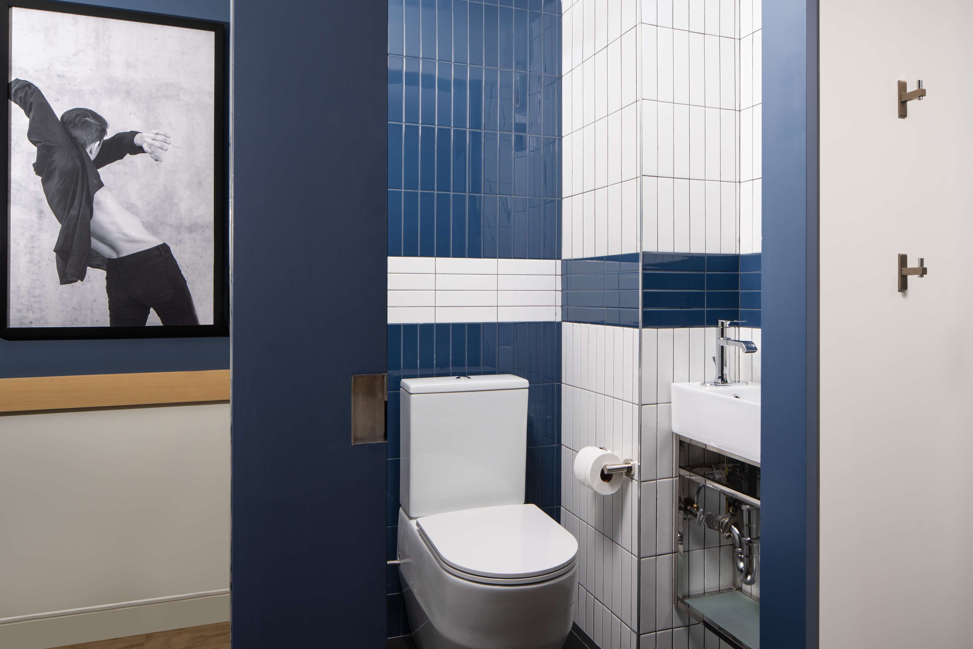 Een moderne badkamer met toilet, wastafel en een ingelijste foto aan de muur.
