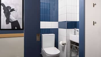 Een moderne badkamer met toilet, wastafel en een ingelijste foto aan de muur.