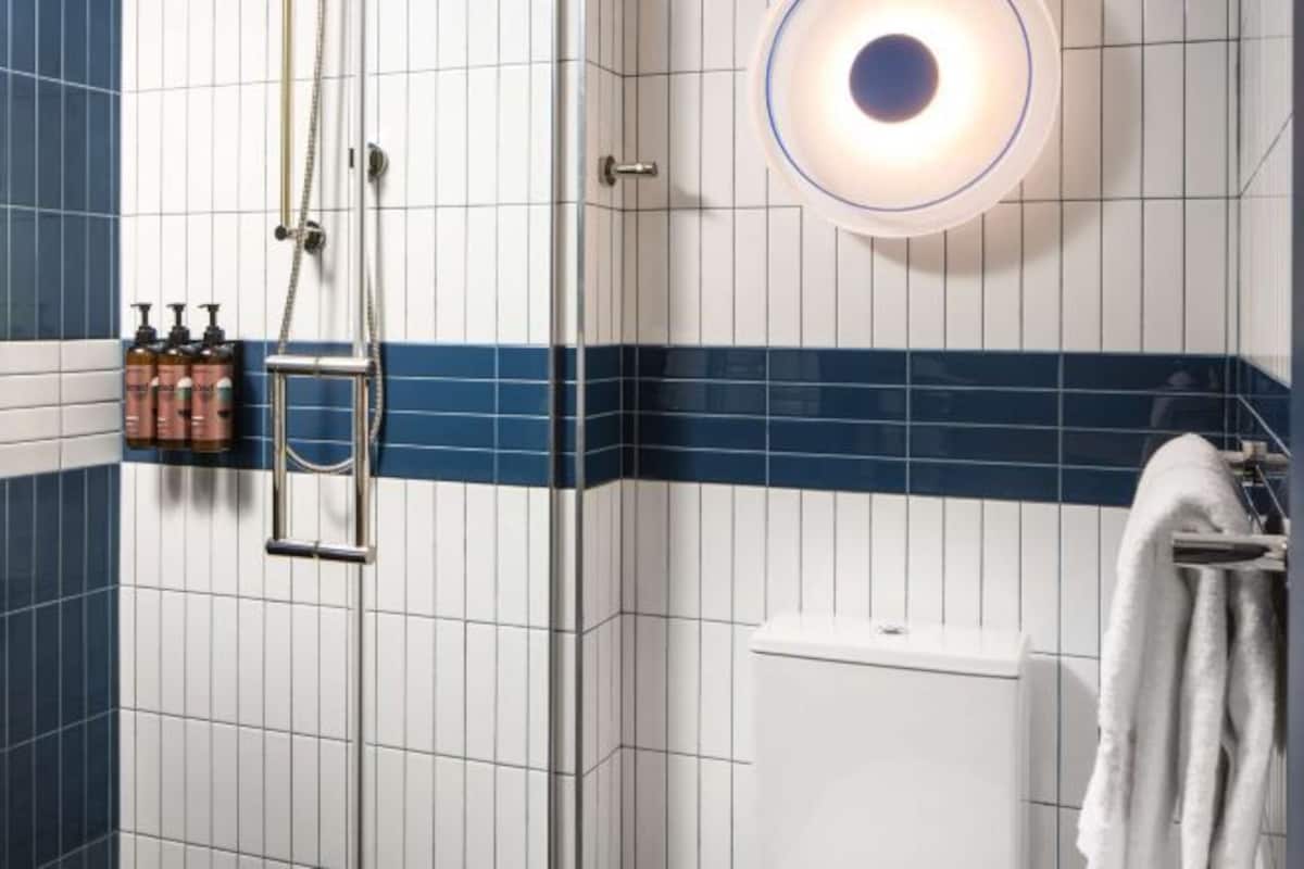 Un baño con ducha, inodoro y un perchero para toallas.