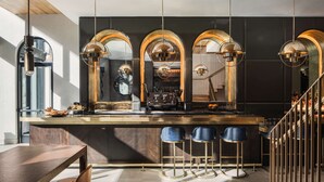 A modern kitchen with a central island, bar stools, and a staircase. - Motto by Hilton New York City Chelsea (New York)