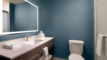 A modern bathroom with a large mirror, two sinks, a toilet, and a towel rack.