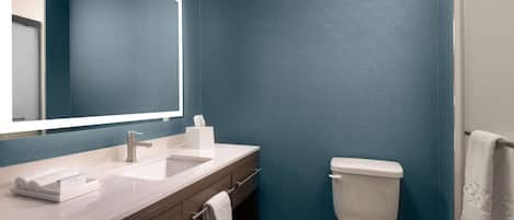 A modern bathroom with a large mirror, two sinks, a toilet, and a towel rack.